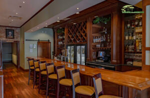 The District Biggs Construction Company, Inc. Custom Cabinetry Wood Bar, with Mirrors and Glass Shelves, Custom Wood Bar and custom wainscoting Bar front. Custom Stained Wood Wine Storage, Wine Glass storage