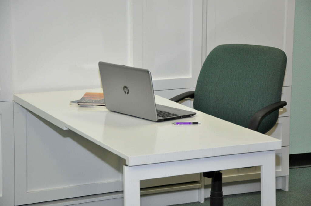 Fold-down desk on the Patrick Murphy Bed, set up as a home office with a laptop and chair