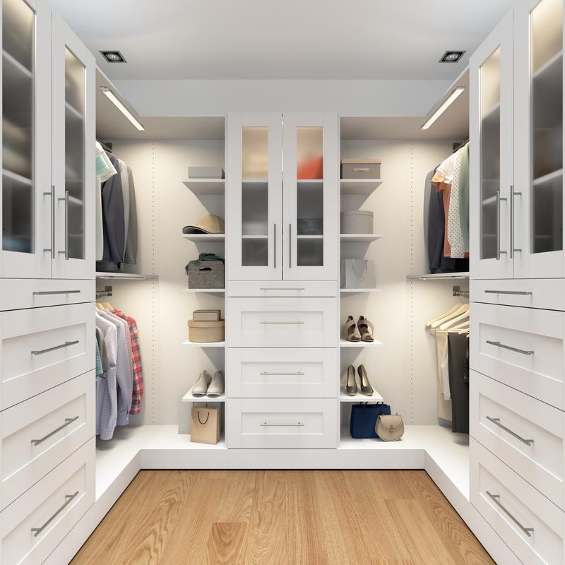 Rendered illustration of a white U-shaped walk-in closet with hanging space, shelves, drawers and glass-front cabinets.